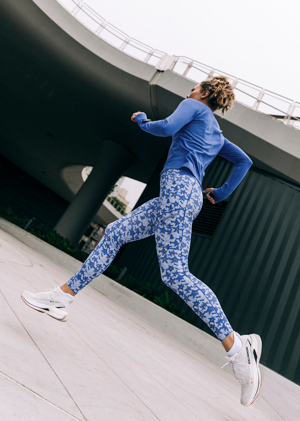 Woman running outside in a blue long sleeve and blue with blue flower print running tights
