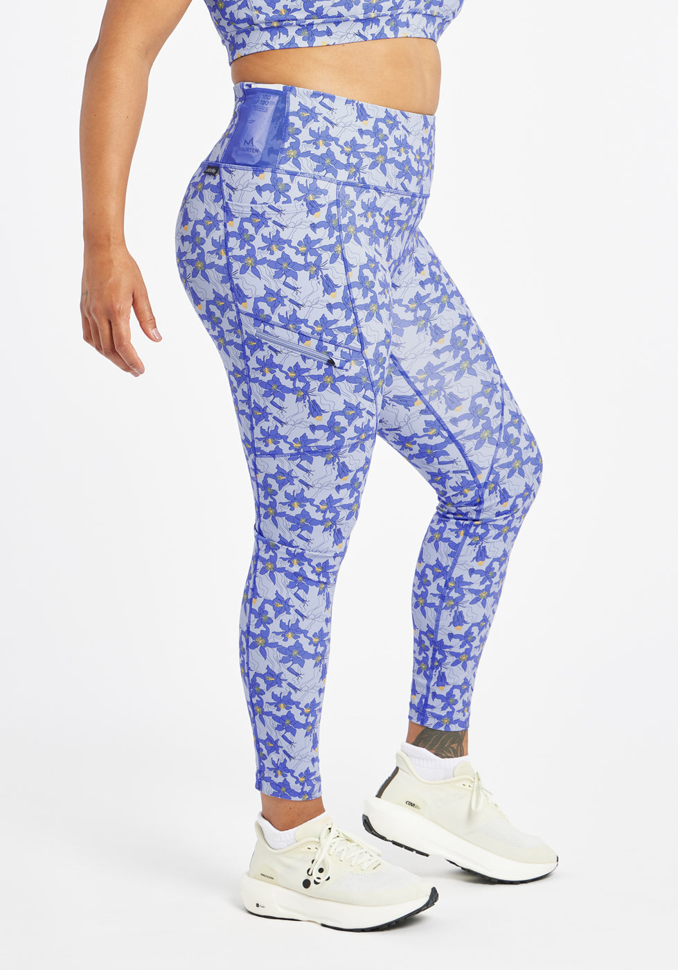 Woman wearing blue with blue flower print running tights in size 12, side view