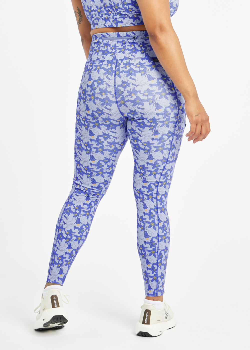 Woman wearing blue with blue flower print running tights in size 12, back view