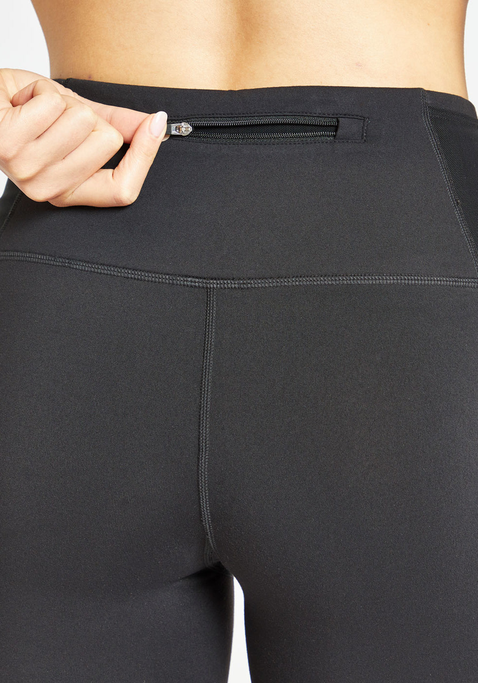 Woman wearing black compression shorts, close up of back zipper pocket