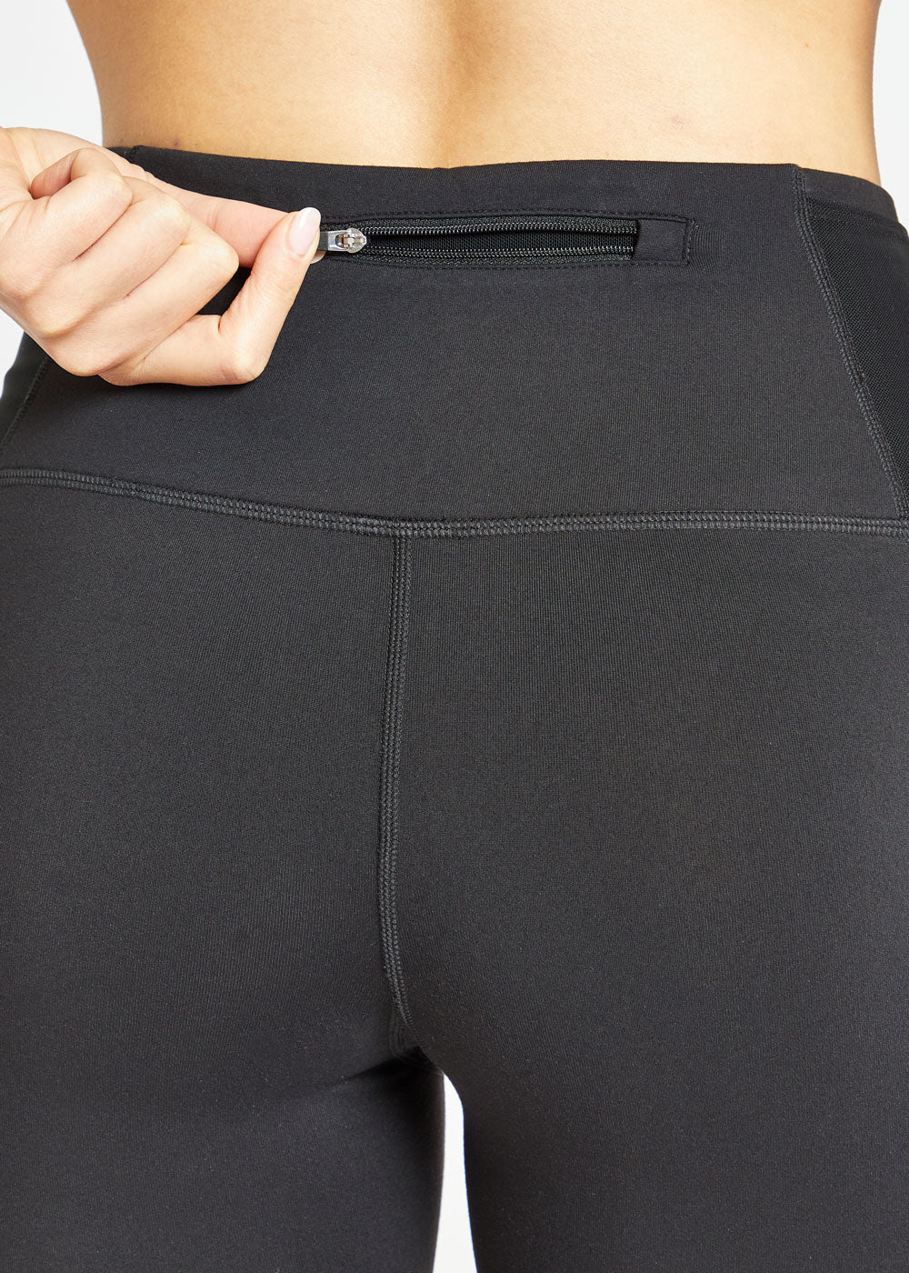 Woman wearing black compression shorts, close up of back zipper pocket
