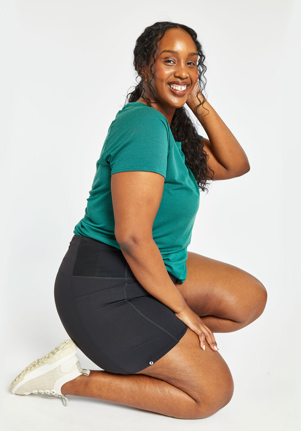 Woman wearing green running top and black compression shorts in size 16/18