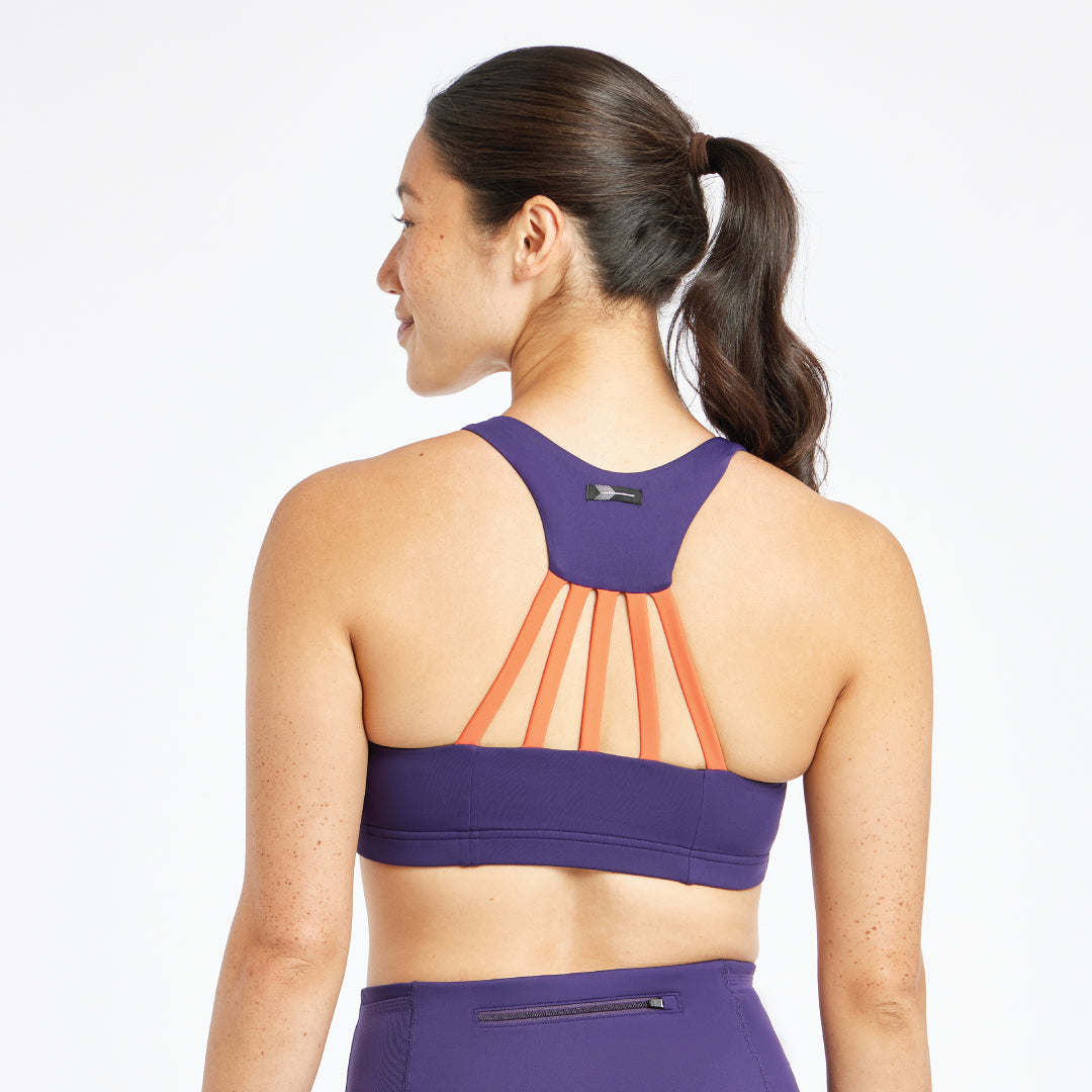 Woman wearing purple and orange Oiselle bra, back view