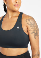 Woman wearing black and white paneled sports bra, close up view of Oiselle branding on chest
