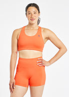 Woman wearing orange and purple paneled sports bra, front view