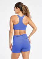 Woman wearing white and blue paneled sports bra, back view