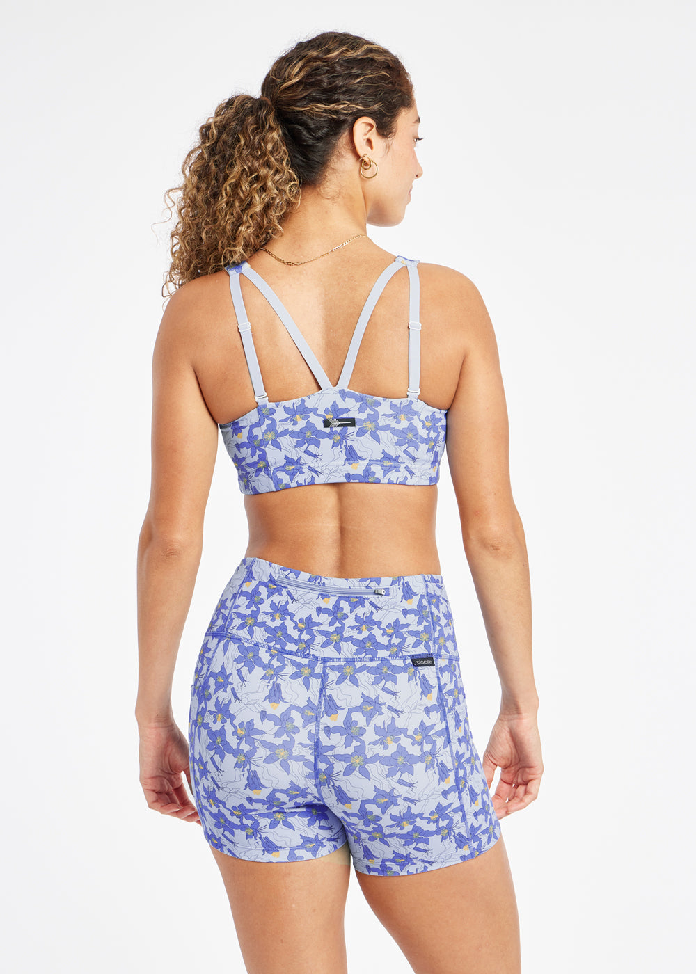 Woman wearing blue with blue floral print sports bra in size 6, back view