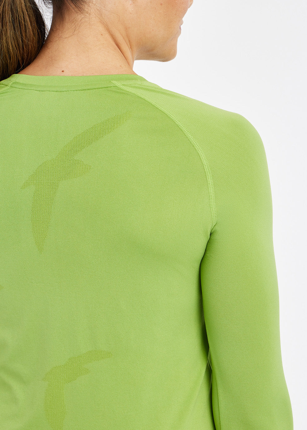 Woman wearing a green running long sleeve, close up of bird details on shirt