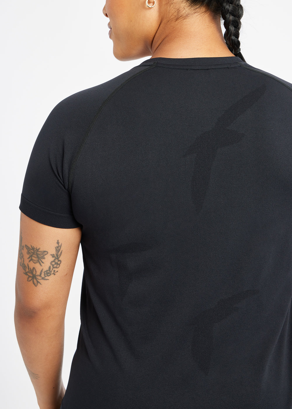 Woman wearing a black running short sleeve, close up of bird details on shirt