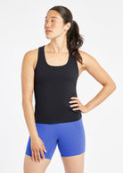 Woman wearing a black running tank top and blue compression shorts, front view