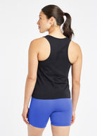 Woman wearing a black running tank top and blue compression shorts, back view