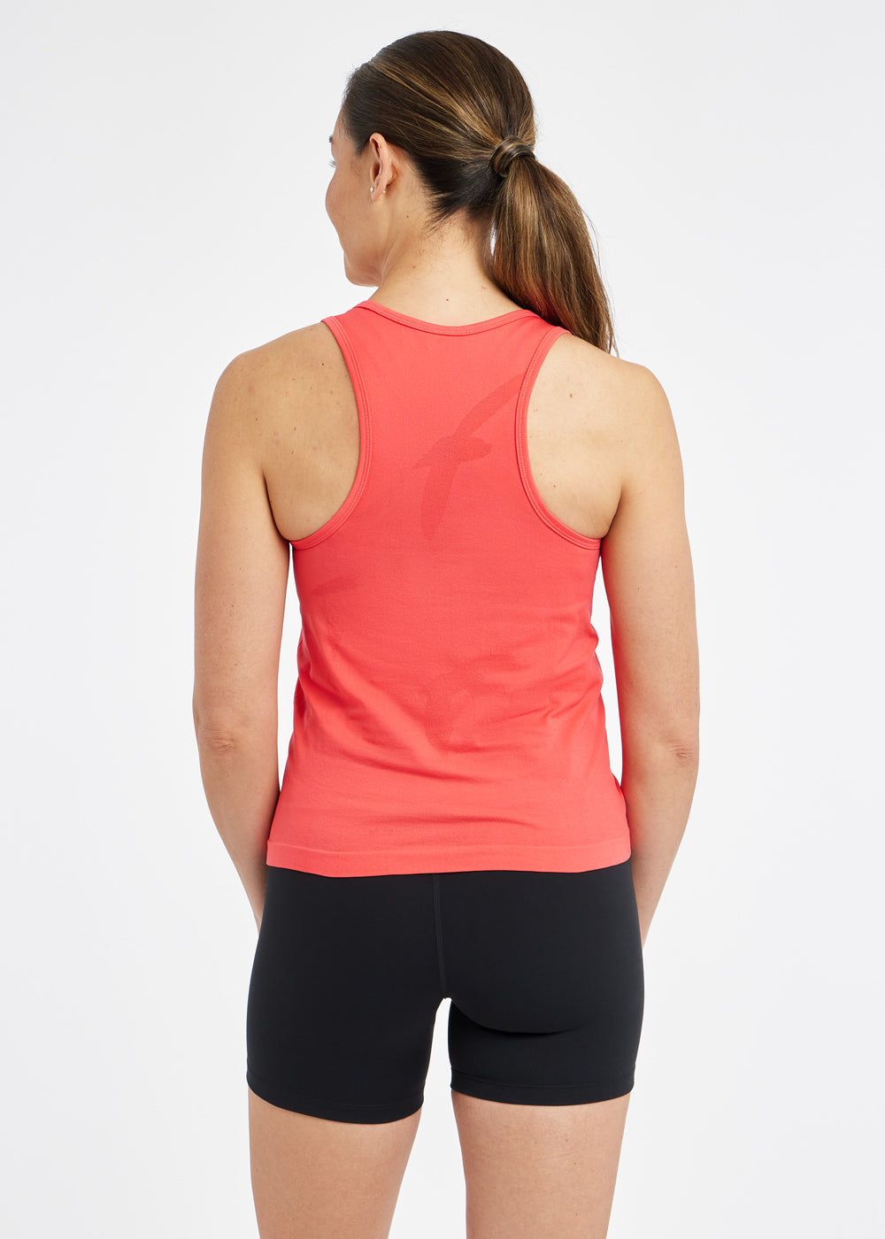 Woman wearing a red orange running tank top and black compression shorts, back view