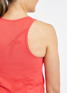 Woman wearing a red orange running tank top, close up of bird details on tank top