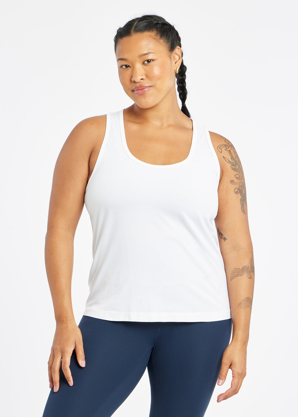 Woman wearing a white running tank top and blue compression tights, front view