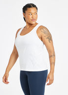 Woman wearing a white running tank top and blue compression tights, side view