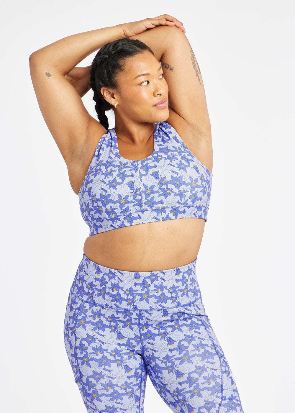 Woman wearing matching blue with blue flower print sports bra and compression shorts in size 12, alternate front view