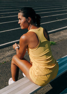 Flyout Chill Racerback Tank in Dawn Patrol, woman sitting on a track
