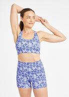 Woman wearing matching blue with blue flower print sports bra and compression shorts in size 6, front view