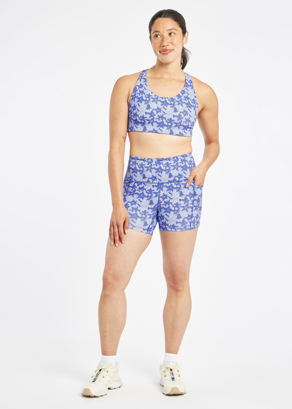 Woman wearing matching blue with blue flower print sports bra and compression shorts in size 6, front view