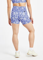 Woman wearing blue with blue flower print compression shorts in size 6, back view