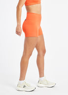 Woman wearing orange compression shorts in size 6, side view