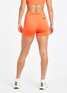 Woman wearing orange compression shorts in size 6, back view