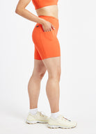 Woman wearing orange compression shorts in size 6, side view
