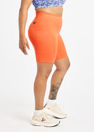 Woman wearing orange compression shorts in size 12, side view