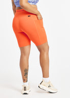 Woman wearing orange compression shorts in size 12, back view