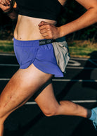 Person running on a track wearing blue Oiselle running shorts
